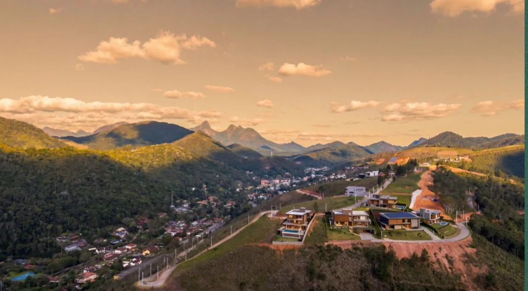 Vista aérea do Golden Green com casas modernas no alto e a Serra de Teresópolis ao fundo